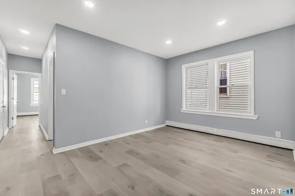 a view of an empty room with wooden floor and a window