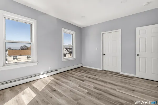 a view of an empty room with window and wooden floor