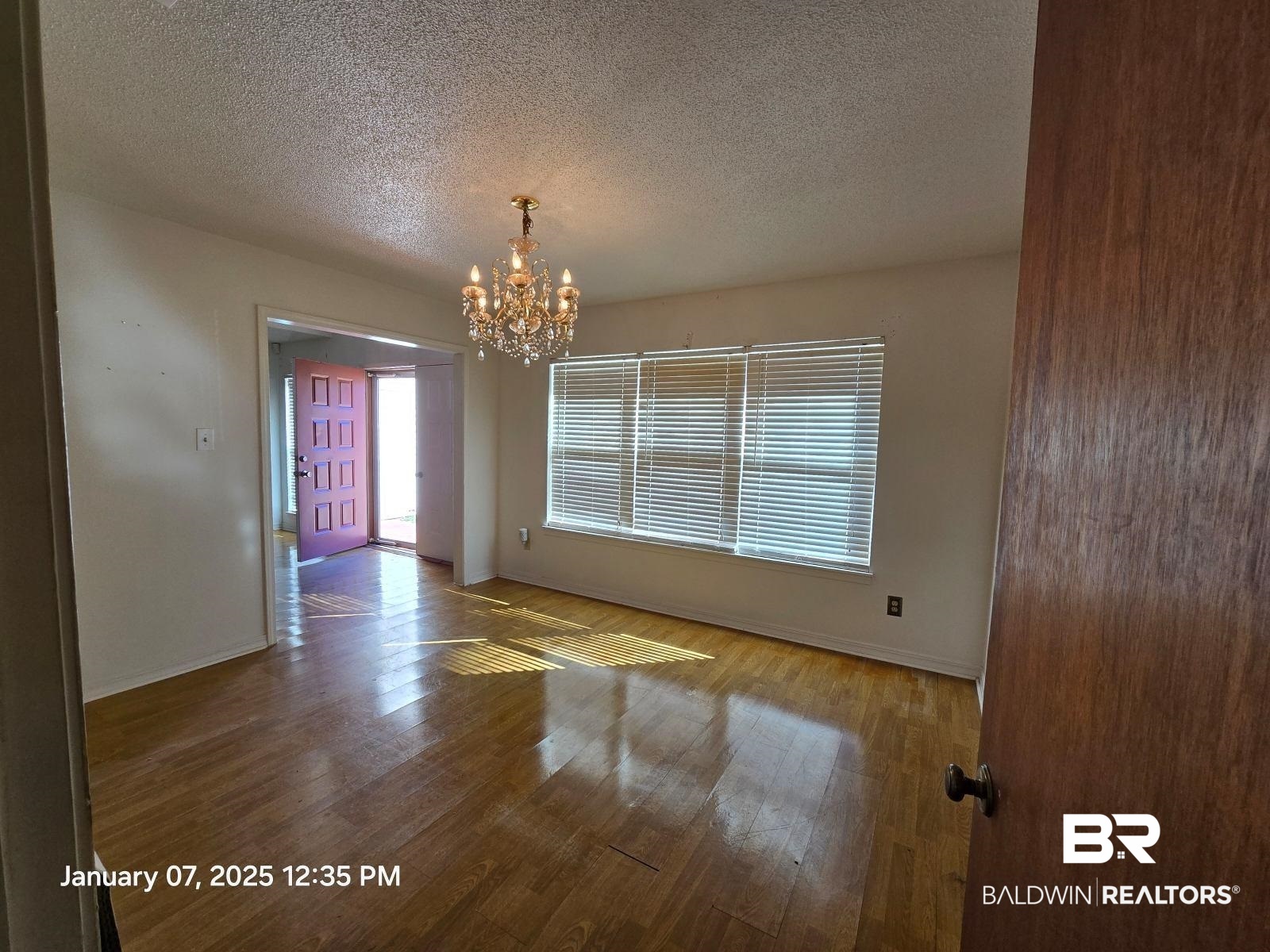 154 Byrd Road Monroeville, AL 36460 - Photo 5 of 26 Unfurnished room featuring a chandelier, hardwood / wood-style floors, and a textured ceiling