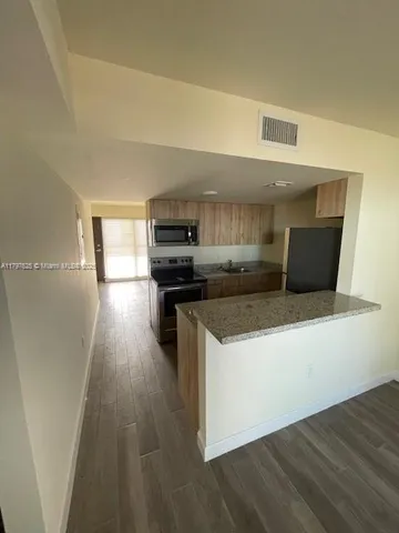 a kitchen with kitchen island wooden floors and appliances