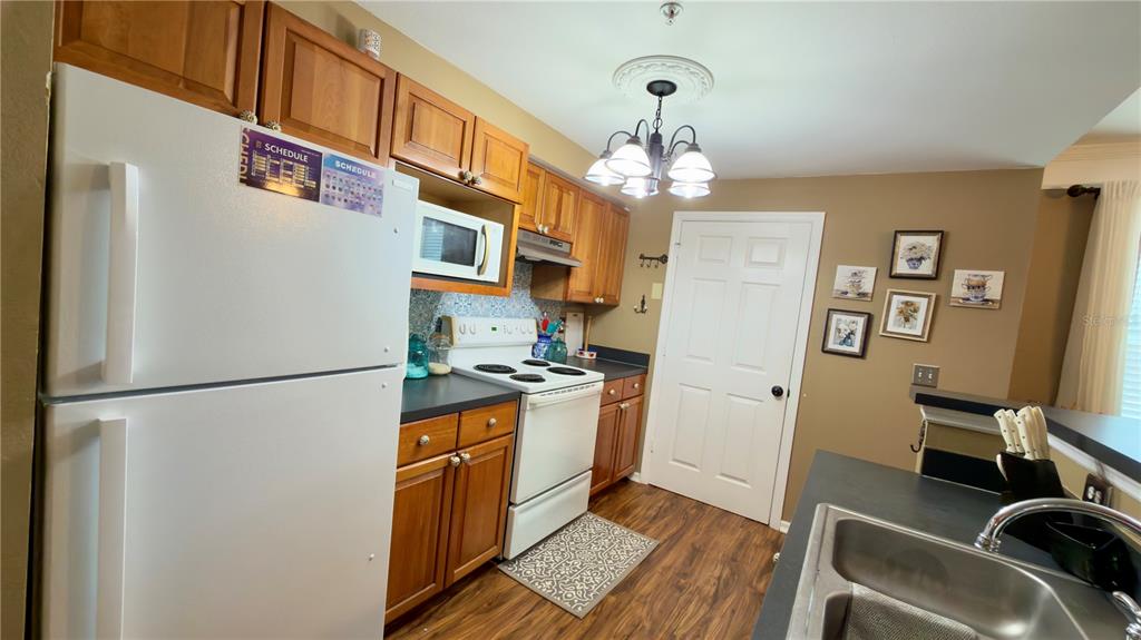 6624 Time Square Avenue, Unit 102 Orlando, FL 32835 - Photo 33 of 96 a kitchen with stainless steel appliances granite countertop a refrigerator a sink dishwasher a stove and a dining table with wooden floor