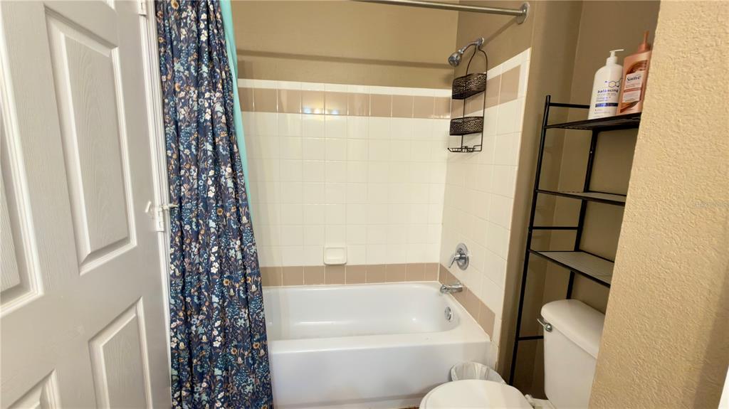 6624 Time Square Avenue, Unit 102 Orlando, FL 32835 - Photo 60 of 96 a bathroom with a shower curtain and a toilet