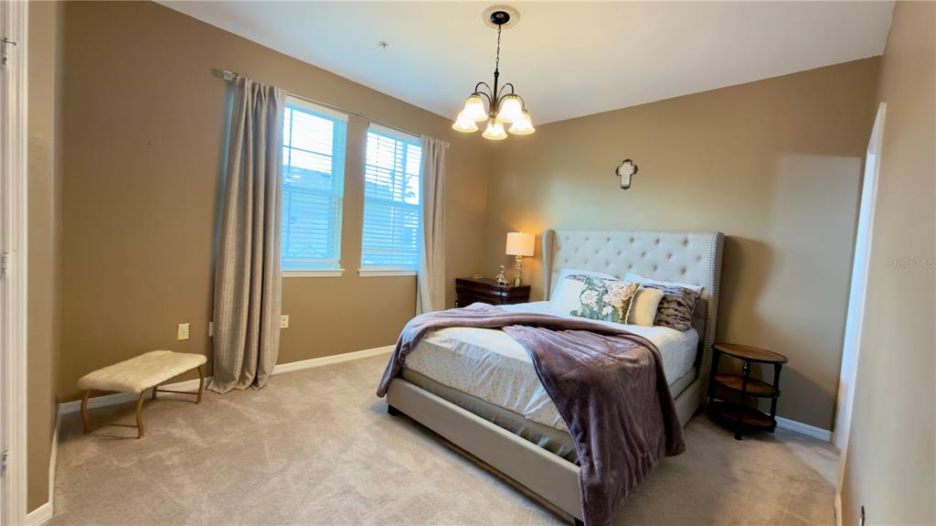 6624 Time Square Avenue, Unit 102 Orlando, FL 32835 - Photo 61 of 96 a spacious bedroom with a bed and a chandelier