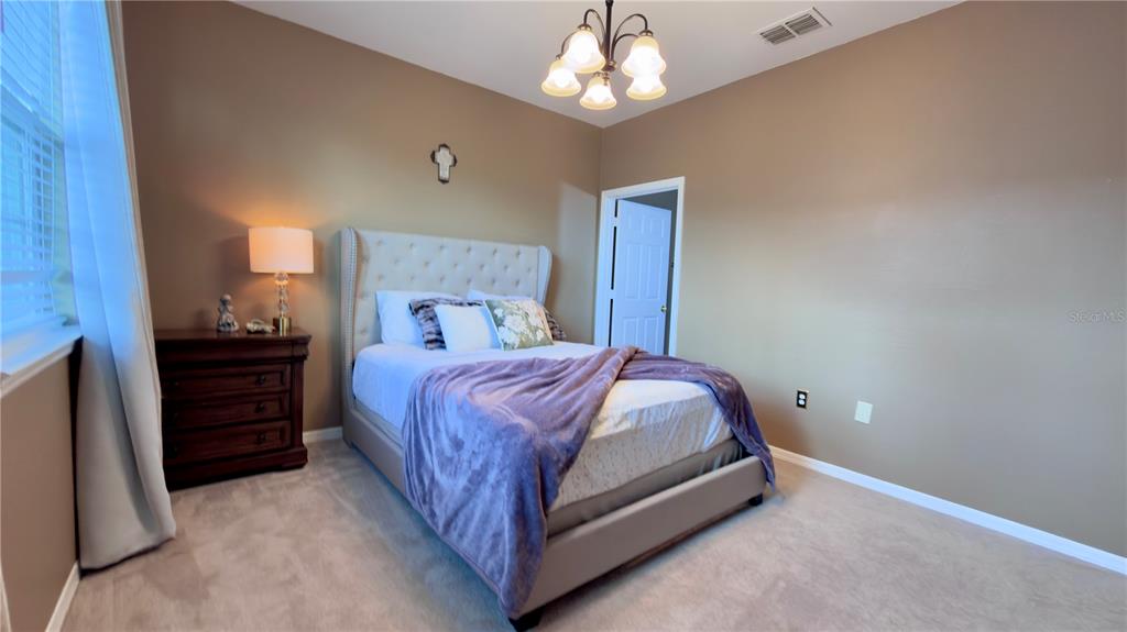 6624 Time Square Avenue, Unit 102 Orlando, FL 32835 - Photo 63 of 96 a spacious bedroom with a bed and a chandelier