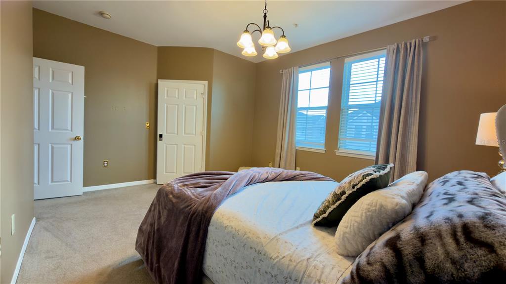 6624 Time Square Avenue, Unit 102 Orlando, FL 32835 - Photo 72 of 96 a bedroom with a bed and a chandelier