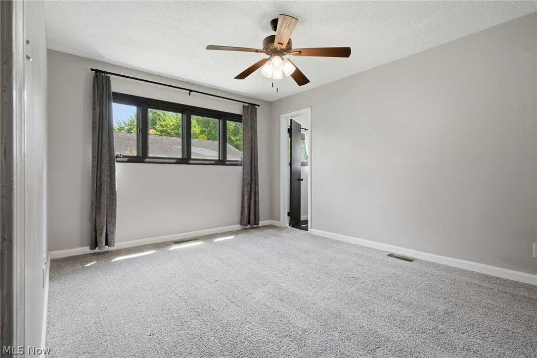 8160 Joyce Road Broadview Heights, OH 44147 - Photo 26 of 45 Carpeted room featuring light gray walls, a multi-pane window with black framing, and a ceiling fan with wood-finish blades