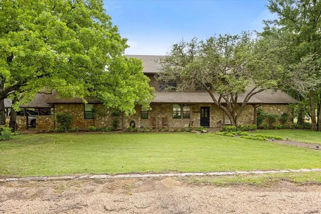 a front view of a house with a garden and trees