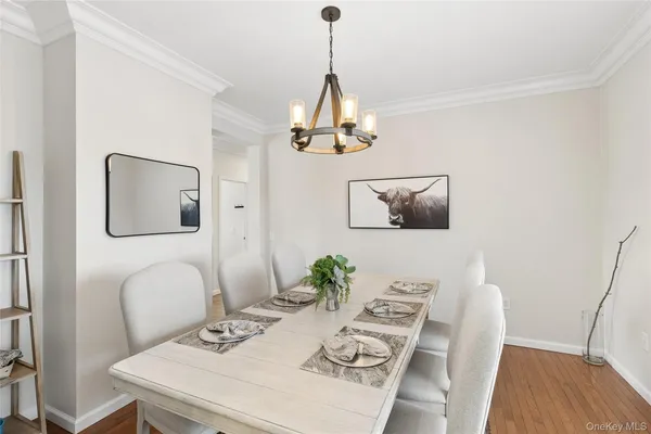 a dining room with wooden floor a chandelier a wooden table and chairs