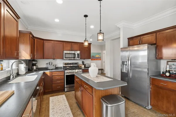 a kitchen with stainless steel appliances a stove a sink a refrigerator a center island and furniture