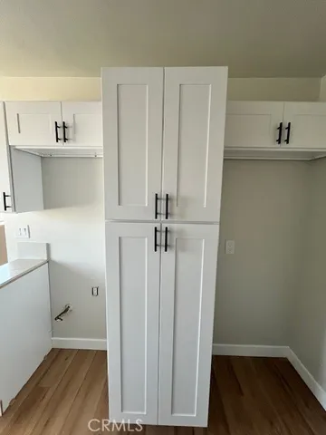 a view of a storage and utility room with wooden floor