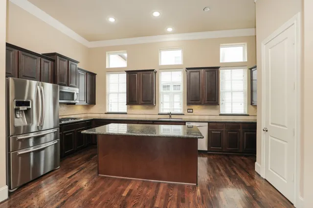 a kitchen with kitchen island granite countertop a sink cabinets and stainless steel appliances