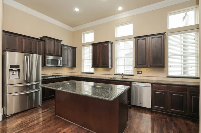 a kitchen with kitchen island granite countertop a sink appliances and cabinets