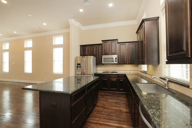 a kitchen with kitchen island granite countertop a sink stove and refrigerator