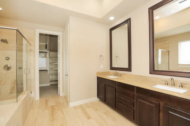 a bathroom with a double vanity sink a large mirror and a bathtub