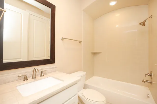 a bathroom with a granite countertop sink toilet and shower