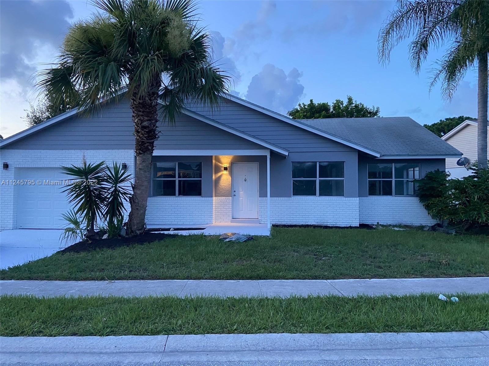 112 Raintree Trail Jupiter, FL 33458 - Photo 1 of 37 a front view of a house with a garden and yard