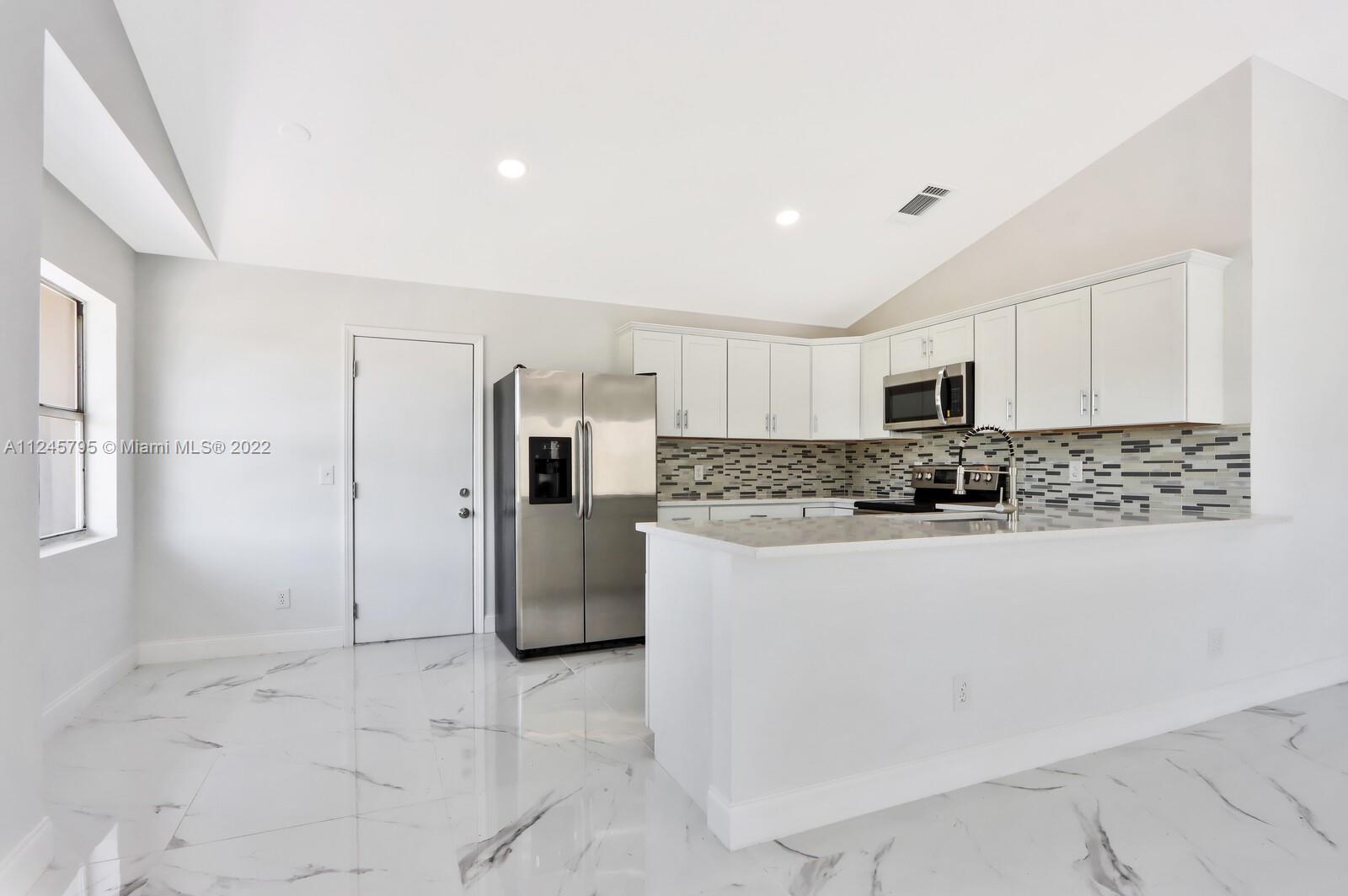 112 Raintree Trail Jupiter, FL 33458 - Photo 17 of 37 a large white kitchen with stainless steel appliances granite countertop a refrigerator a stove a sink and white cabinets