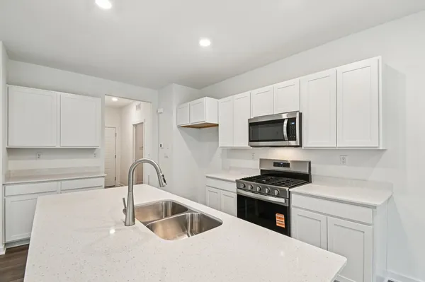 a kitchen with granite countertop a sink and a stove top oven with white cabinets