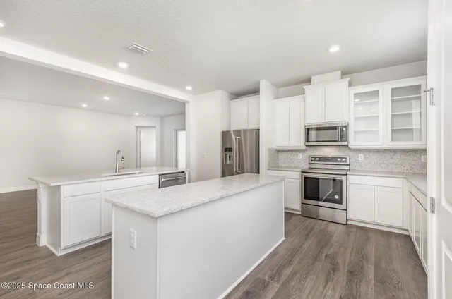 a kitchen with stainless steel appliances kitchen island granite countertop a stove a sink and a refrigerator