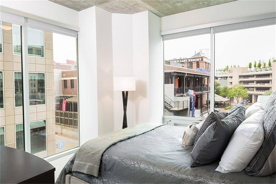 a bedroom with a bed and a large window with balcony view