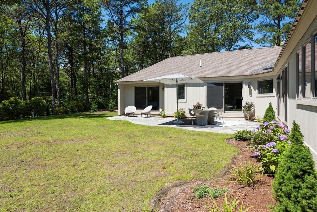 148 Paddock Circle Mashpee, MA 02649 - Photo 26 of 28 a view of a patio with table and chairs potted plants and large tree
