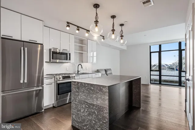 a kitchen with stainless steel appliances granite countertop a refrigerator a stove a sink dishwasher and a refrigerator with wooden floor