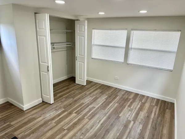 a view of an empty room with wooden floor and closet
