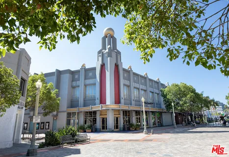 a front view of a building with a garden and trees