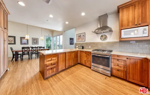 a large kitchen with stainless steel appliances granite countertop a stove and a wooden floors