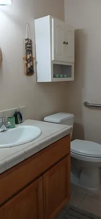 a bathroom with a granite countertop sink a toilet and mirror