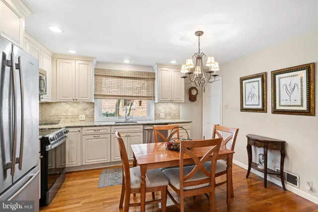 a kitchen with stainless steel appliances granite countertop a dining table chairs and chandelier