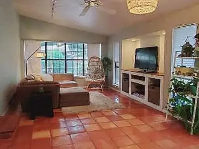 a living room with furniture a flat screen tv and a floor to ceiling window