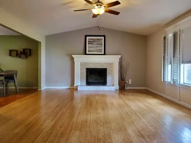 an empty room with windows fireplace and wooden floor