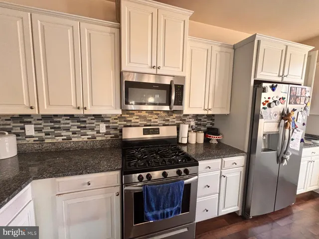 a kitchen with granite countertop a refrigerator stove and microwave