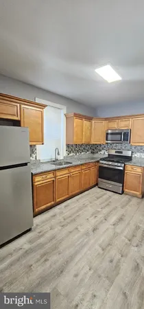 a large kitchen with stainless steel appliances granite countertop a stove and a refrigerator