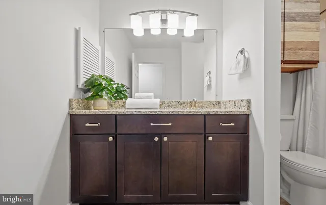 a bathroom with a granite countertop sink a mirror and a toilet