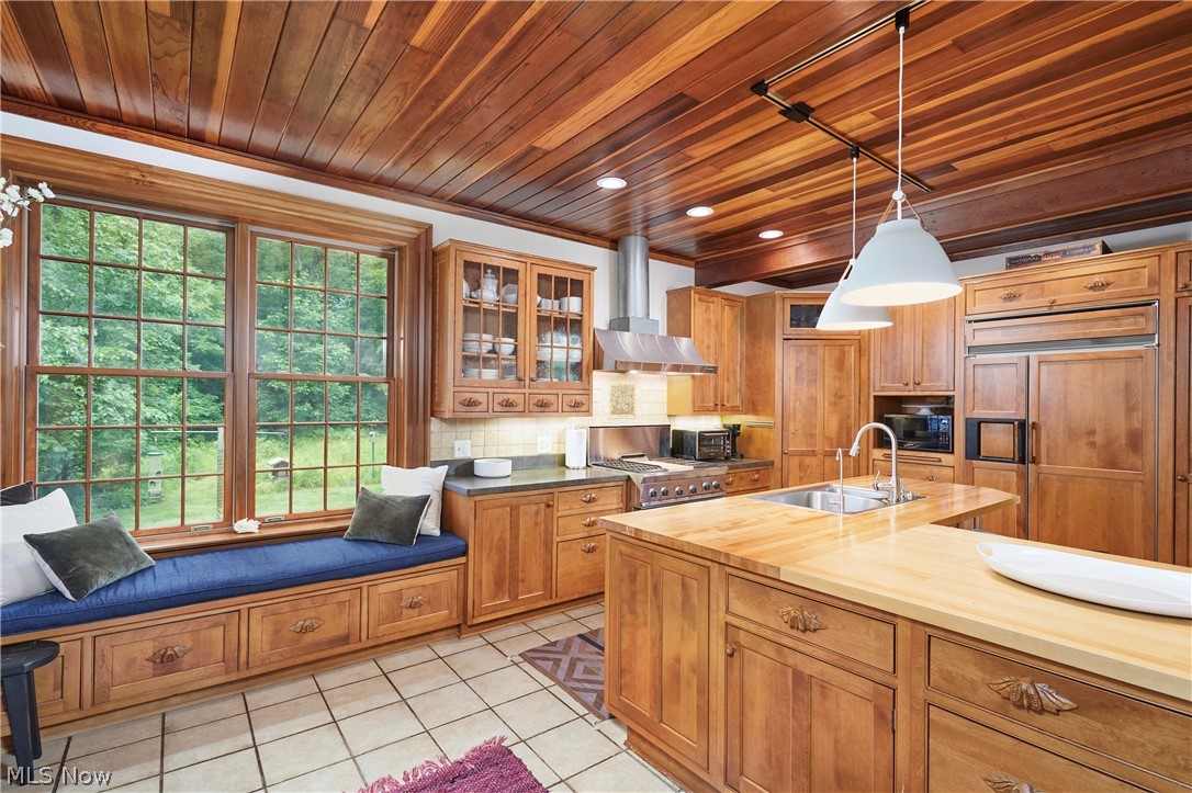 5046 Alger Road Richfield, OH 44286 - Photo 24 of 49 Kitchen featuring a wood-finish plank ceiling, large window with built-in bench seating, wood cabinetry, tile flooring, and a central island with a sink and wood countertop