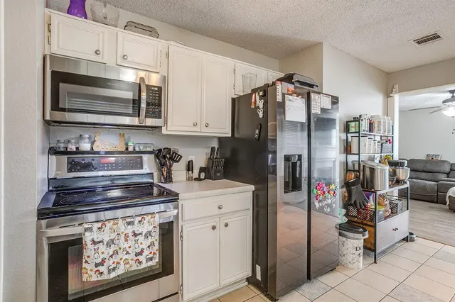 a kitchen with stainless steel appliances granite countertop a refrigerator stove and white cabinets