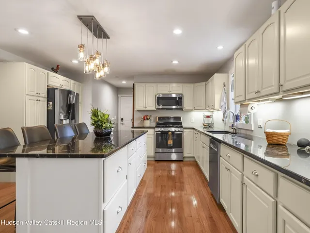 a spacious bedroom with a bed a dresser and wooden floor