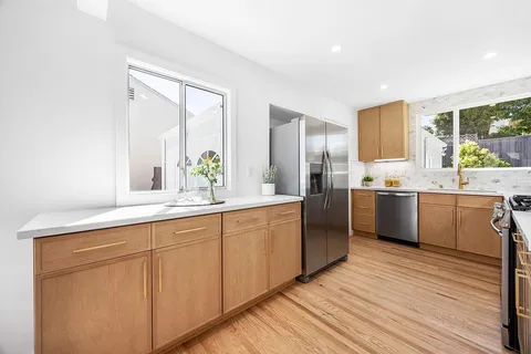 a kitchen with a sink cabinets stainless steel appliances and windows