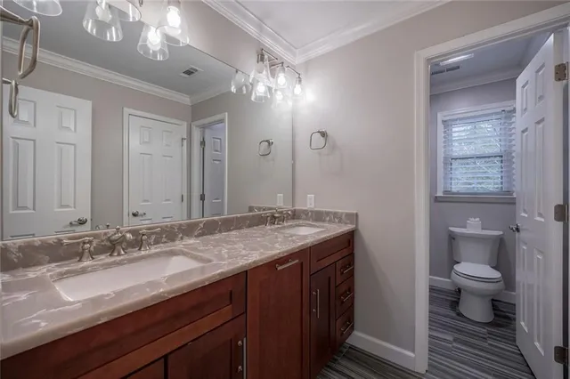 a bathroom with a granite countertop sink a toilet and a mirror