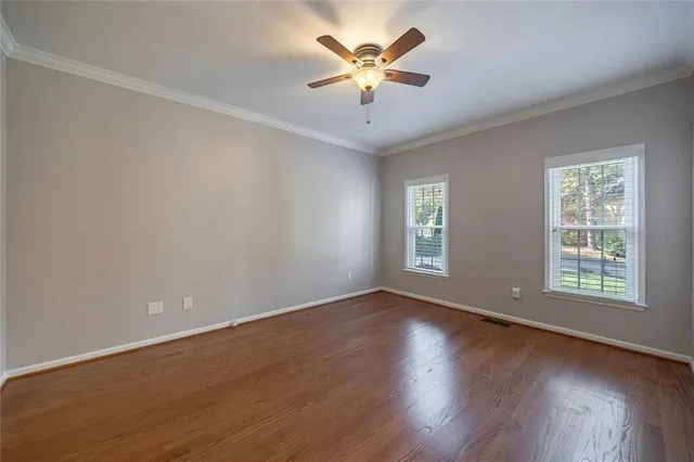 a view of an empty room with window and wooden floor