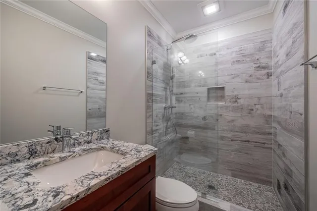 a bathroom with a granite countertop sink toilet a mirror and shower