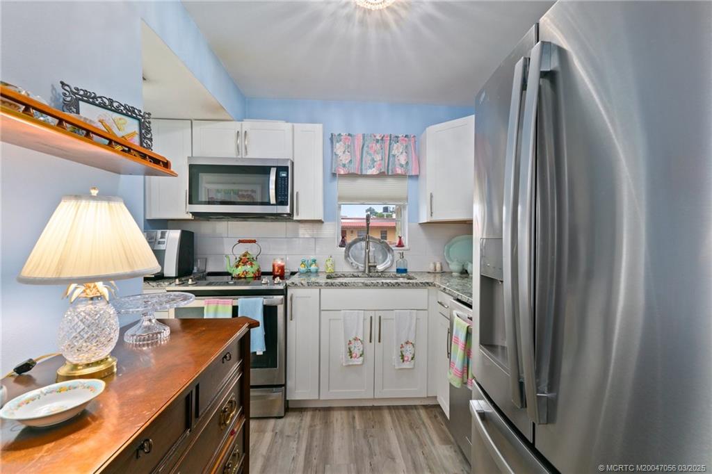1985 Southwest Palm City Road, Unit 44I Stuart, FL 34994 - Photo 11 of 31 a kitchen with stainless steel appliances granite countertop a stove top oven a sink dishwasher and a refrigerator with wooden floor