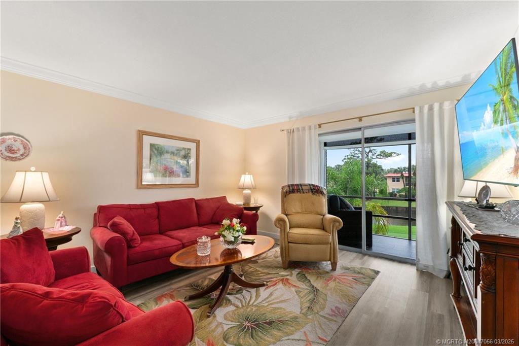 1985 Southwest Palm City Road, Unit 44I Stuart, FL 34994 - Photo 13 of 31 a living room with furniture a flat screen tv and a floor to ceiling window