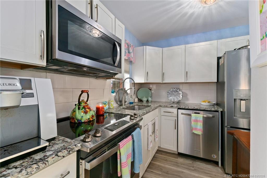 1985 Southwest Palm City Road, Unit 44I Stuart, FL 34994 - Photo 9 of 31 a kitchen with stainless steel appliances granite countertop a stove top oven a sink and dishwasher