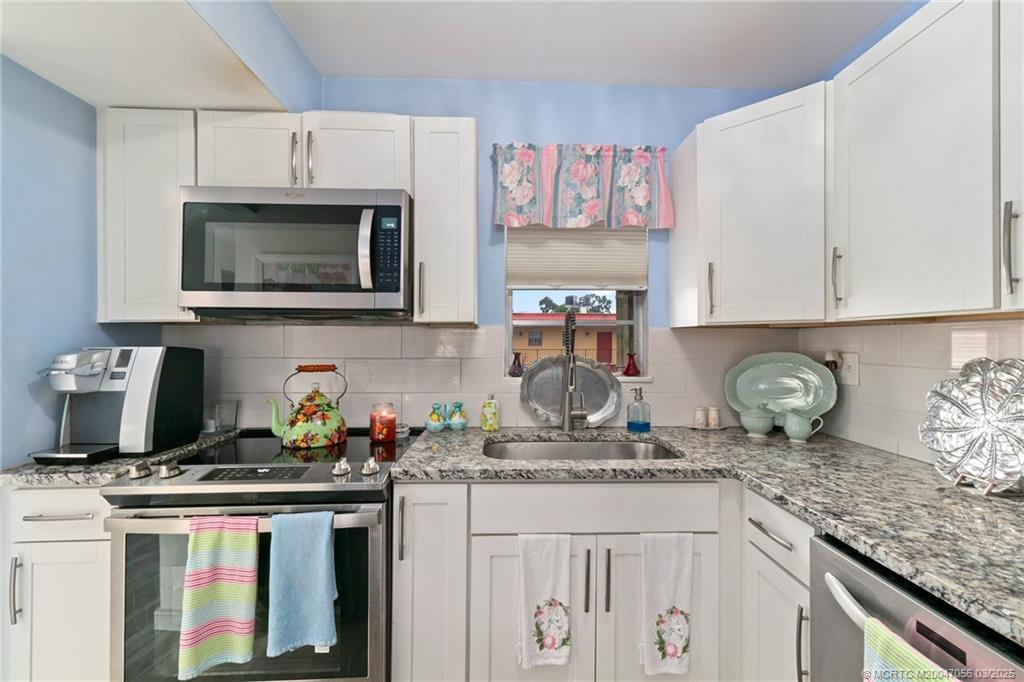 1985 Southwest Palm City Road, Unit 44I Stuart, FL 34994 - Photo 10 of 31 a kitchen with granite countertop a stove top oven microwave and cabinets