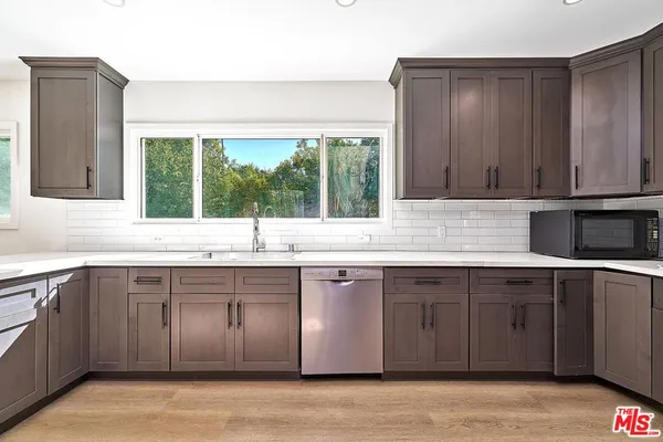 a kitchen with stainless steel appliances granite countertop a refrigerator a stove and a sink with wooden floor