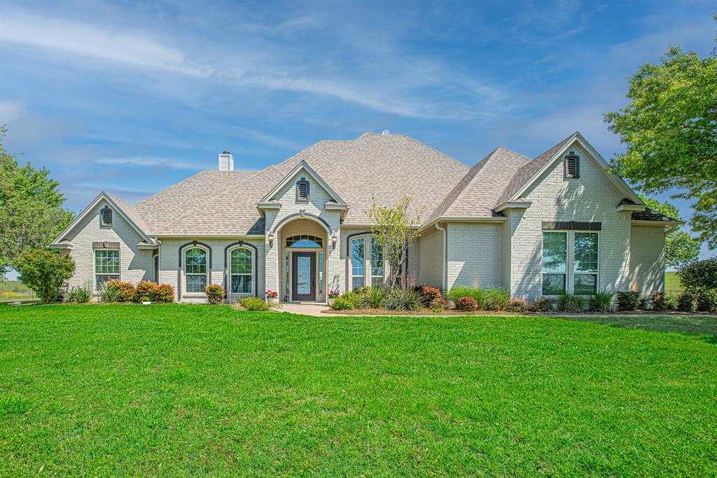 a front view of a house with a yard and trees