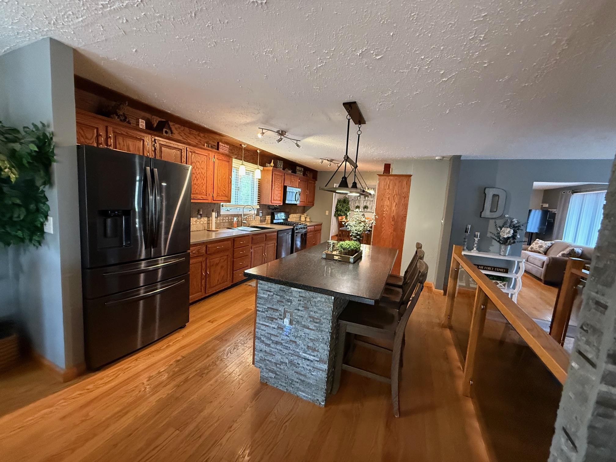 7758 Ray Court Roscoe, IL 61073 - Photo 3 of 37 a kitchen with stainless steel appliances kitchen island granite countertop a refrigerator a stove a dining table and chairs with wooden floor